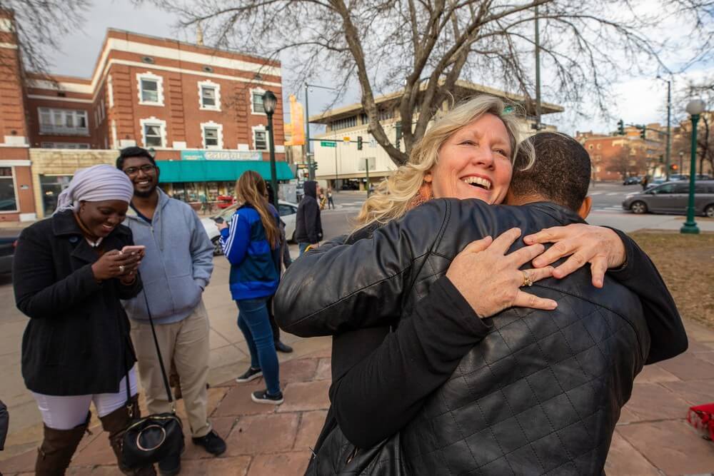 american woman smiles and hugs african international student